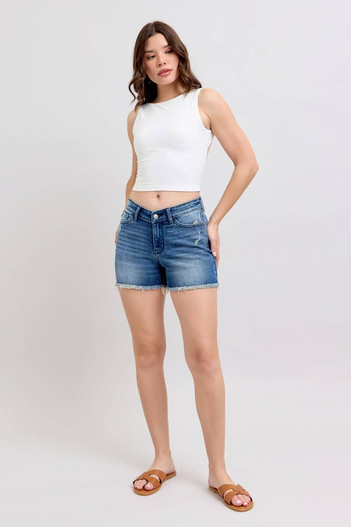 Woman wearing a white sleeveless top and blue denim shorts on a white background