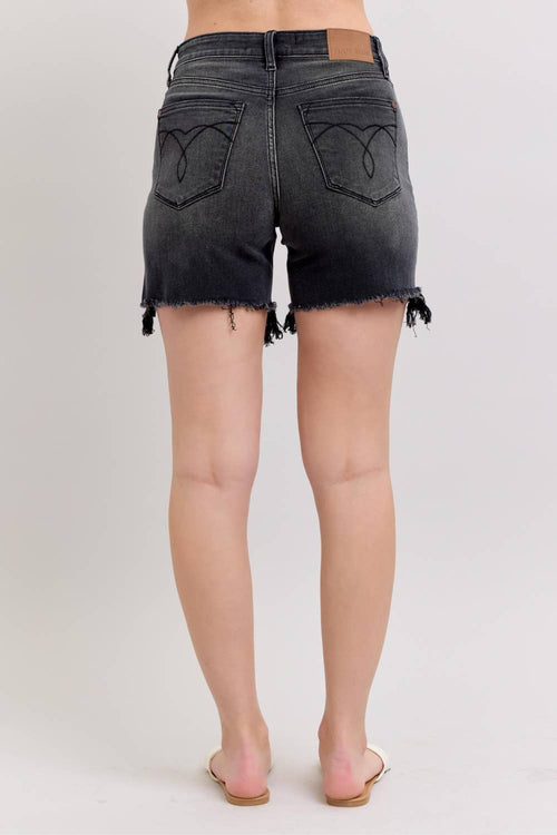 Black denim shorts worn by a person on a plain background