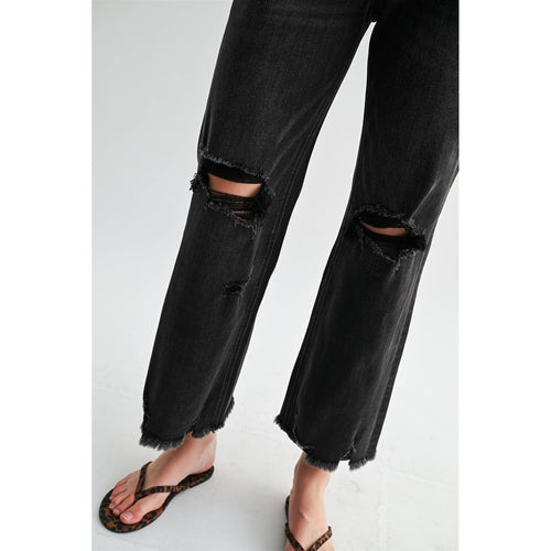 Black distressed jeans worn by a person on a white background