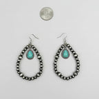 Pair of beaded earrings with turquoise stones on a white surface, next to a quarter for scale.
