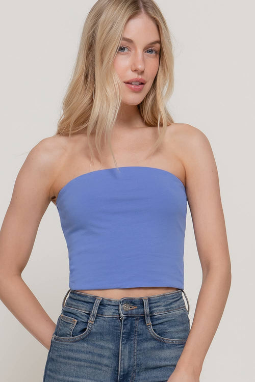 Woman wearing a blue strapless top and jeans on a plain background