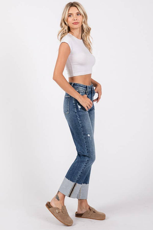 Woman wearing a white crop top and blue jeans on a white background