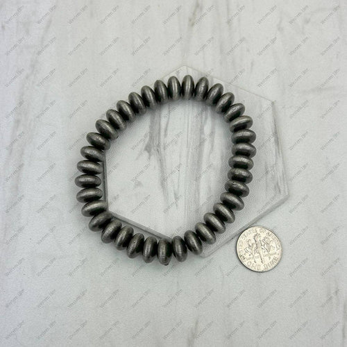 Hexagonal metallic object with a coin for scale on a marble surface