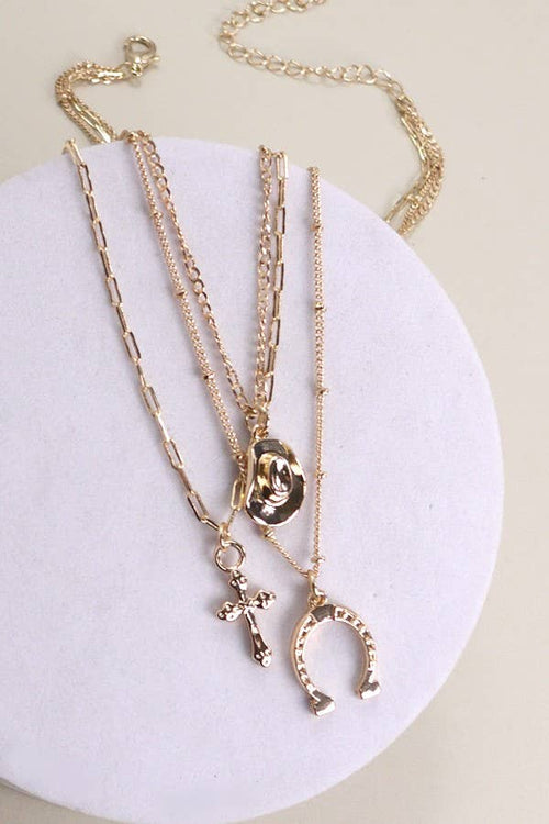 Set of gold necklaces with various pendants on a white circular stand.