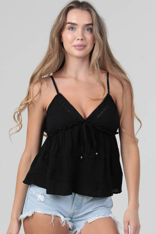 Woman wearing a black top and denim shorts on a plain background