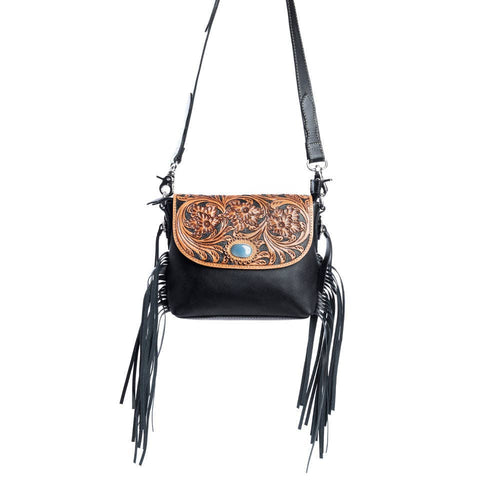 Black leather crossbody bag with brown tooled leather flap and black fringe on a white background