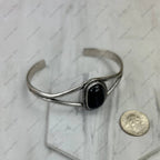 Silver bracelet with a black stone on a marble surface