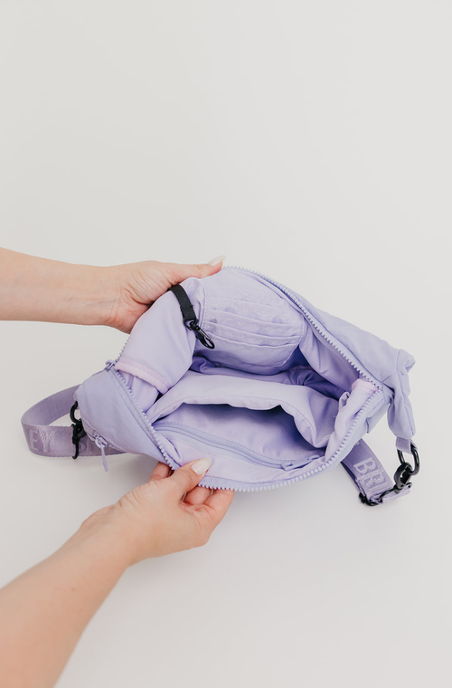 Purple backpack held by a person on a light gray background