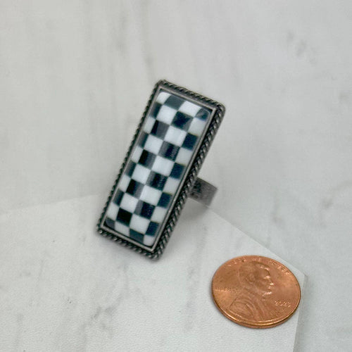 Checkered ring on a marble surface with a penny for scale