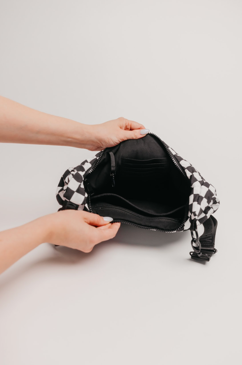 Person holding a black and white checkered bag against a light gray background