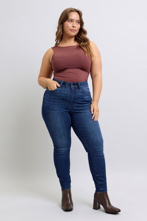 Woman wearing blue jeans and a brown top on a white background