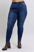 Blue jeans worn by a person on a plain background