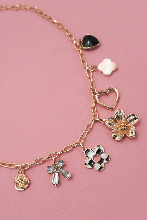 Gold bracelet with various charms on a pink background