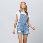 Woman wearing a denim overall outfit on a plain background