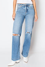 Light blue high-waisted straight-leg jeans with distressed rips at the knees, shown on a model wearing white pointed-toe boots against a white studio background.