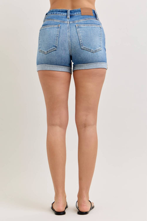 Denim shorts worn by a person on a plain background
