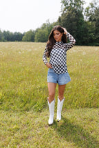 Woman in a checkered shirt and denim shorts standing in a field