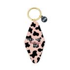 Keychain with cow print design and text on a white background