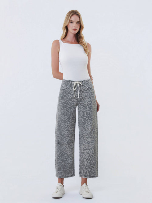 Woman wearing a white tank top and patterned pants on a white background