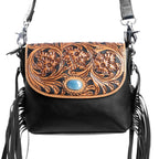 Black handbag with floral tooled leather design and tassels on a white background