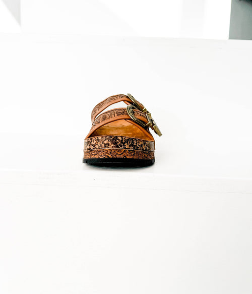 Brown sandal with decorative patterns on a white background