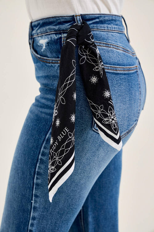 Person wearing blue jeans with a black bandana tied around the waist on a white background