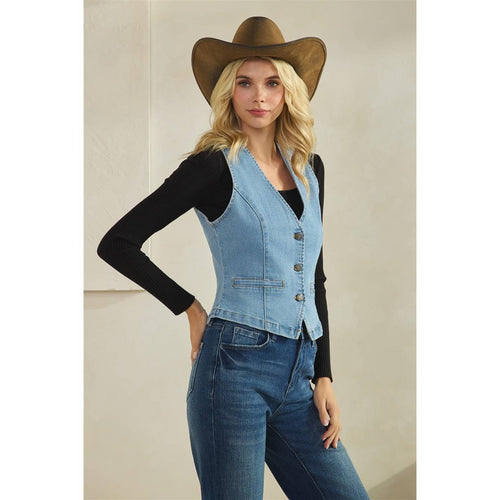Woman wearing a denim vest and cowboy hat against a plain background
