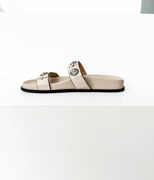 Beige sandal with decorative straps on a white background
