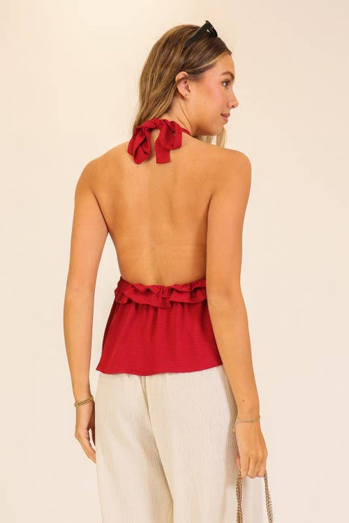 Woman wearing a red halter top with ruffled details on a beige background