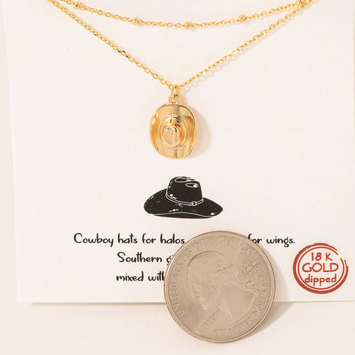 Gold necklace with a pendant on a card featuring text and a coin.