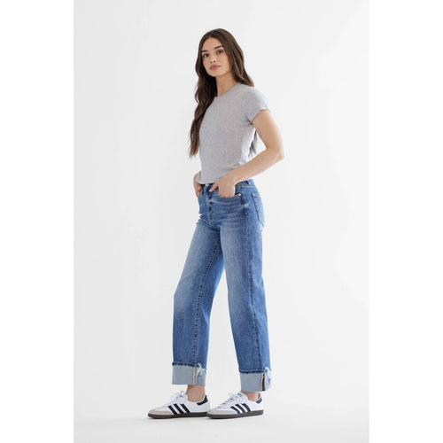 Woman wearing a gray t-shirt and blue jeans with white sneakers on a white background