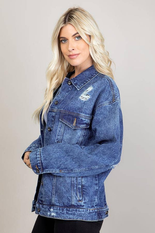 Woman wearing a blue denim jacket with a subtle pattern on a plain background