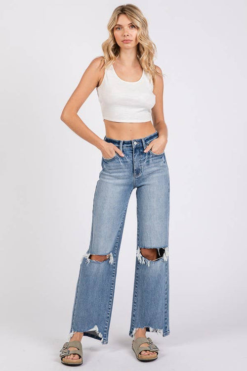 Woman wearing a white crop top and blue jeans on a white background