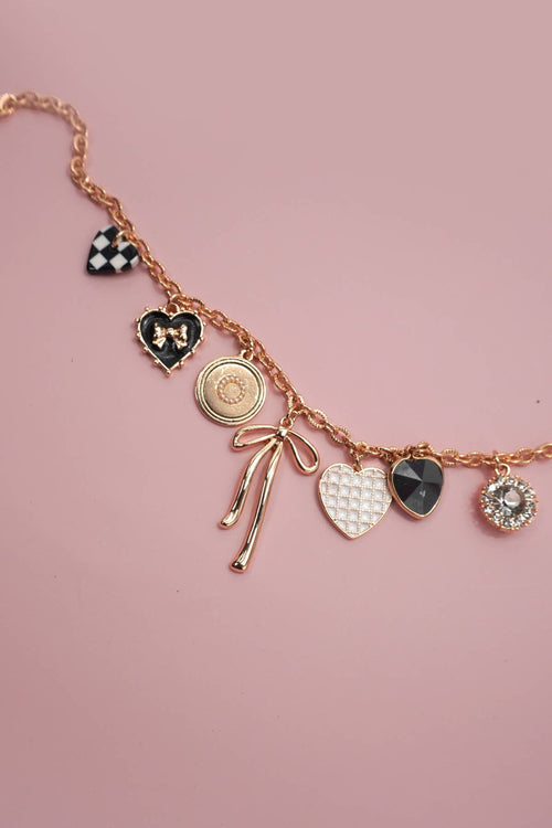 Necklace with various charms on a pink background