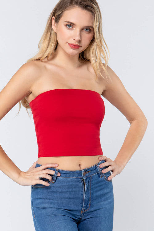 Woman wearing a red strapless top and blue jeans on a white background