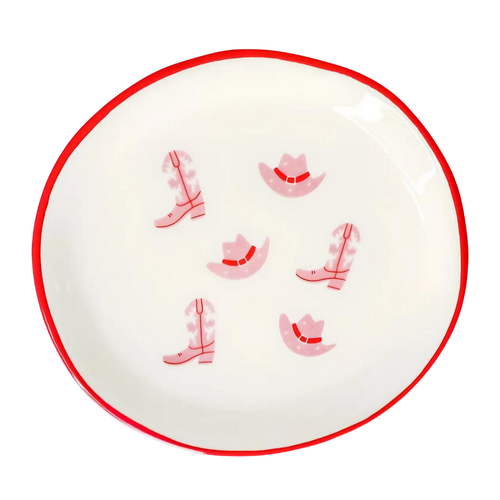Round white plate with red rim featuring pink cowboy boot and hat designs on a white background
