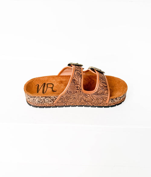 Brown sandal with intricate design on a white background