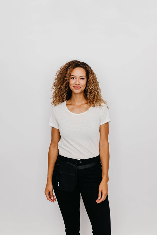 Woman wearing a white t-shirt and black pants against a plain background