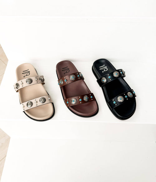 Three sandals in beige, brown, and black with embellishments on a white background