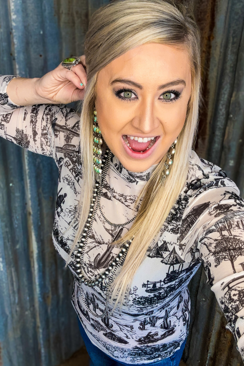 Woman with blonde hair and patterned sweater standing against a corrugated metal wall.