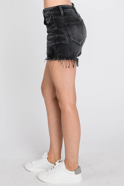 Person wearing black denim shorts on a white background