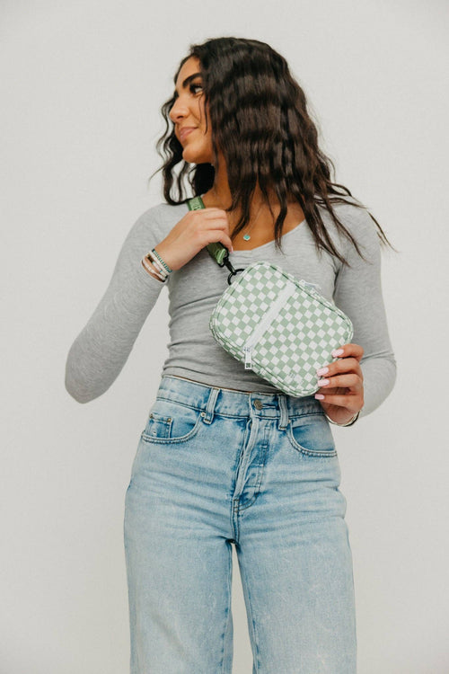 Woman holding a green and white checkered bag against a plain background