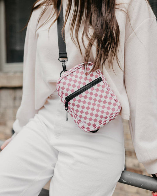 Person wearing a pink checkered crossbody bag outdoors
