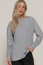 Woman wearing a gray oversized long-sleeve shirt against a plain background