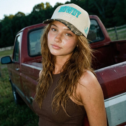 Woman wearing a 'Howdy' cap in front of a red truck