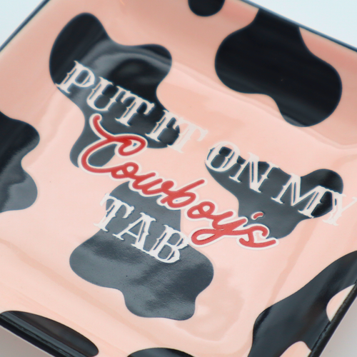Cow print product with text 'Put it on my cowboy's tab' on a light blue background