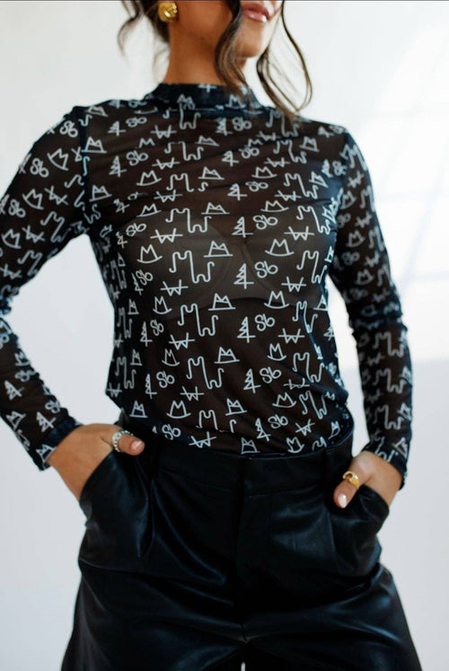Person wearing a black long-sleeve shirt with white cat pattern on a plain background