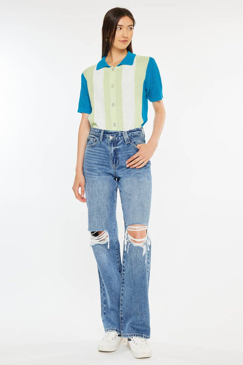 Person wearing a colorful striped shirt and ripped jeans on a white background