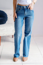 Person wearing blue jeans standing on a white floor with a blurred background