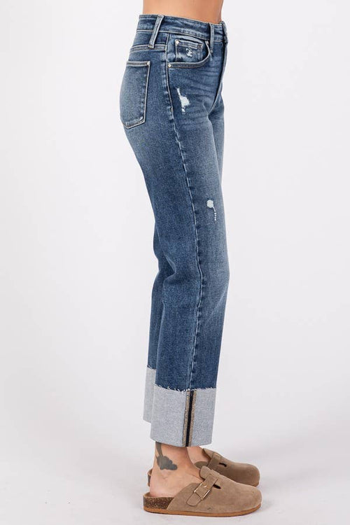 Blue jeans with a distressed look worn by a person on a white background
